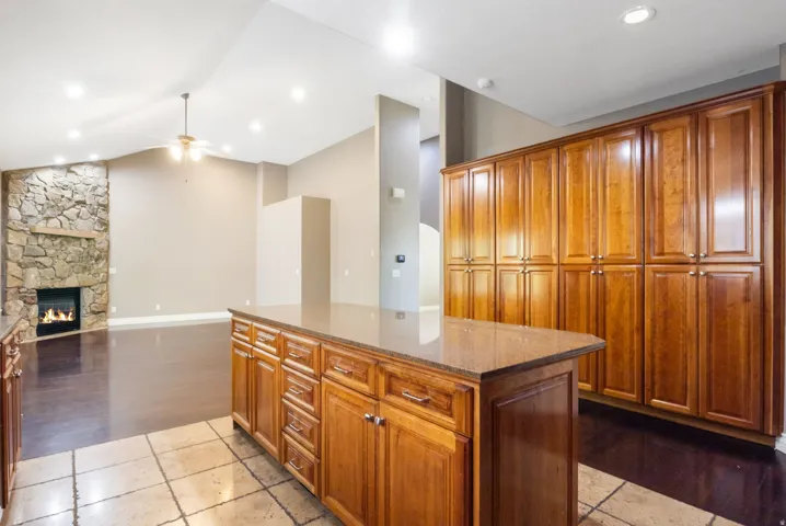 Spacious living area featuring a floor-to-ceiling stone fireplace, vaulted ceiling with a ceiling fan, and recessed lighting