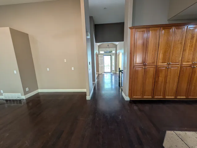 Dark wood-finish flooring throughout, tall ceilings, built-in wood cabinetry, and a prominent entryway