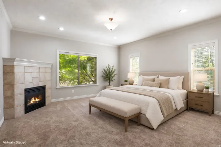 Carpeted interior featuring a fireplace with tile surround, crown molding, recessed lighting, and multiple windows