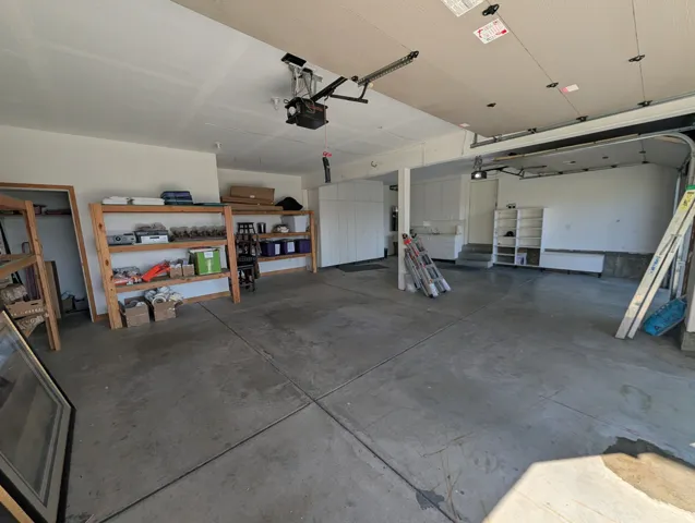 Concrete flooring, built-in cabinetry, and overhead garage door mechanism