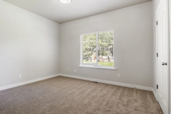 Neutral-toned carpeting, light gray wall paint, and a window with white blinds