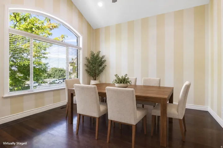 Vaulted ceiling, dark wood-finish flooring, striped wall treatment, arched window, and white trim
