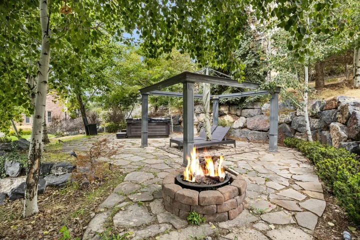 Flagstone patio featuring a built-in fire pit, a metal pergola, and a hot tub