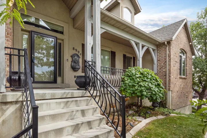 Brick and stucco exterior with covered porch, decorative porch railings, and arched window