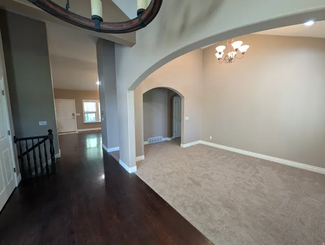 Arched entryways, coffered ceiling, wood-finish flooring, and neutral carpeting
