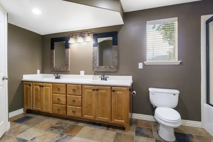 Double vanity with light wood cabinetry, dual sinks, and white countertops