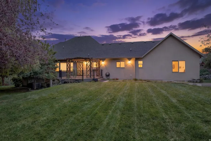 Expansive backyard with a manicured lawn, an elevated deck featuring decorative railing, and a stucco exterior