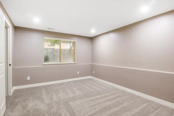 Plush carpeting, recessed lighting, neutral wall tones, white trim, and a window with blinds