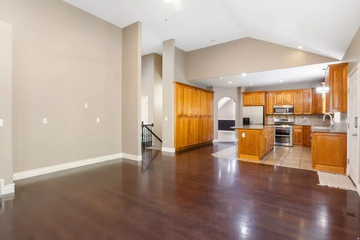 Hardwood-style flooring throughout the main living area, vaulted ceiling, kitchen island, stainless steel double oven, and wood-finish cabinetry