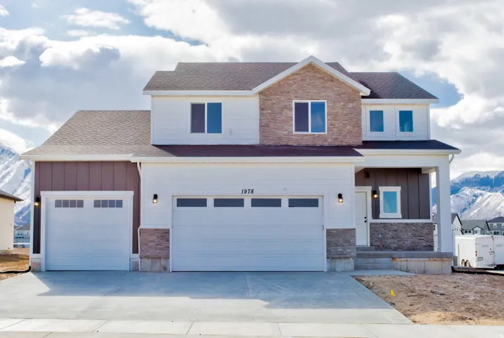 Two-story residence featuring a combination of white siding and stone veneer accents