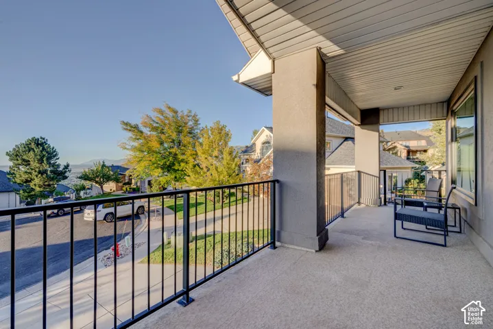 Covered concrete balcony with dark metal railings and a textured stucco exterior
