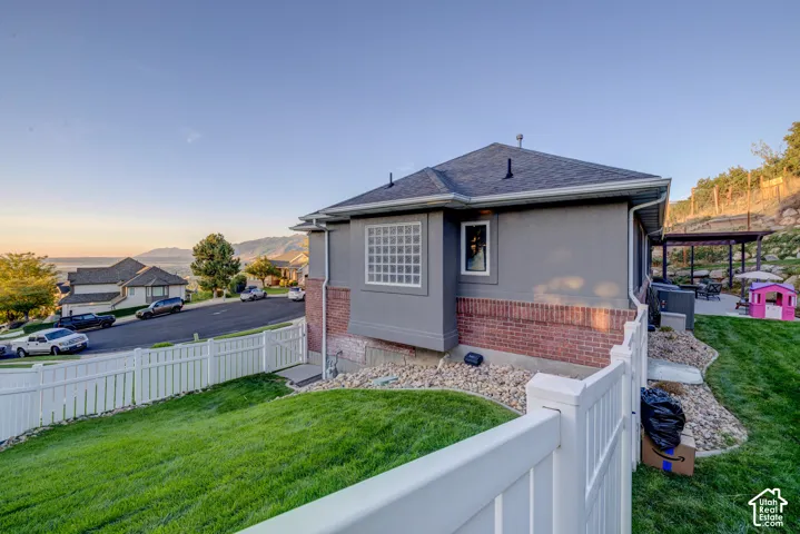 Exterior featuring stucco and brick finishes, a white picket fence, a covered patio structure, and a terraced landscaped yard