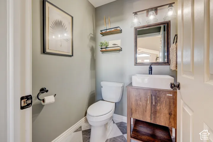 Bathroom featuring a wood-finish vanity with an undermount sink, a framed mirror, and a wall-mounted light fixture