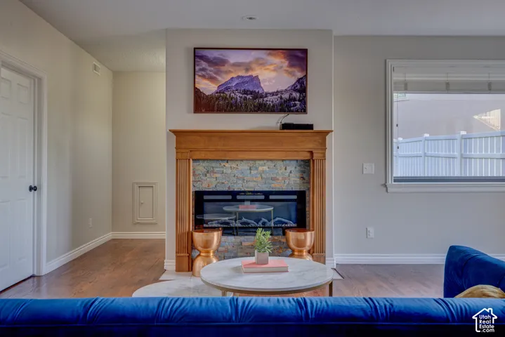 Hardwood-style flooring extends throughout, complementing the fireplace featuring a wood mantel and stone surround