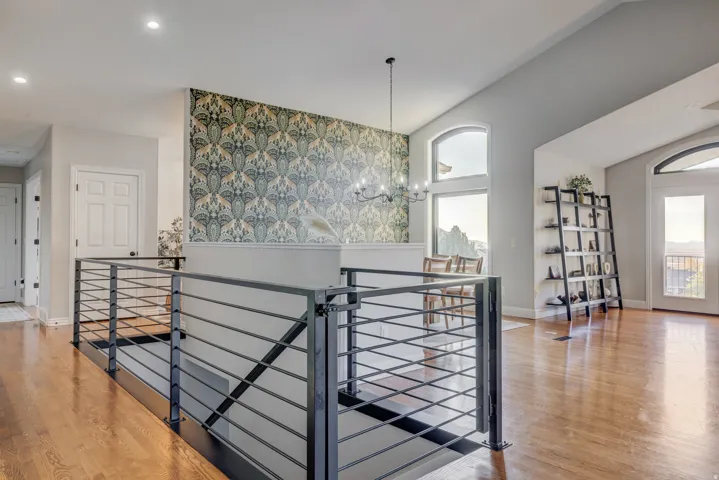 Hardwood flooring, wrought iron railing, vaulted ceilings, arched windows, and a decorative accent wall