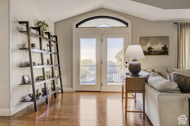 Vaulted ceiling with an arched transom window, French doors, wood-finish flooring, and crown molding