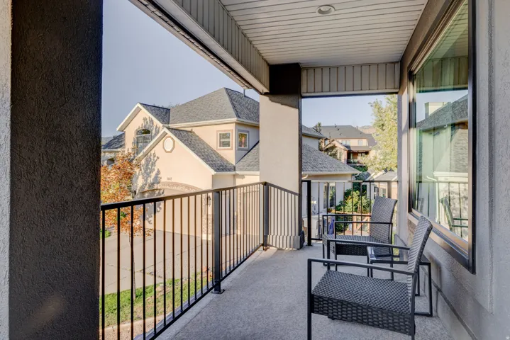 Balcony featuring a black metal railing, concrete flooring, and a textured stucco exterior wall