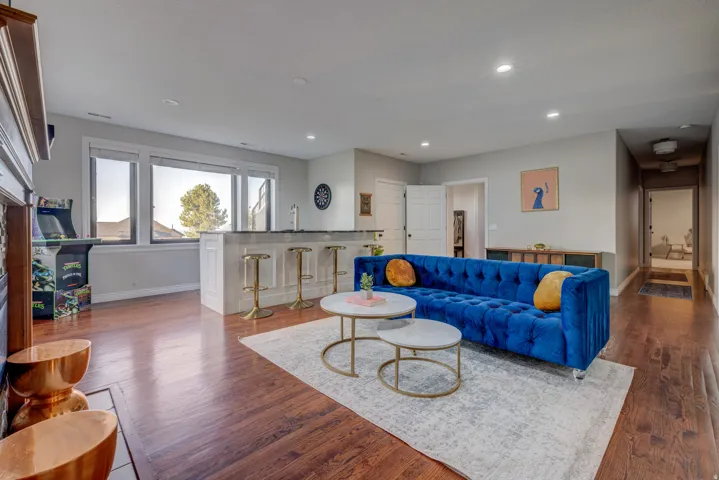 Rich wood-finish flooring, built-in wet bar with seating, recessed lighting, and large windows