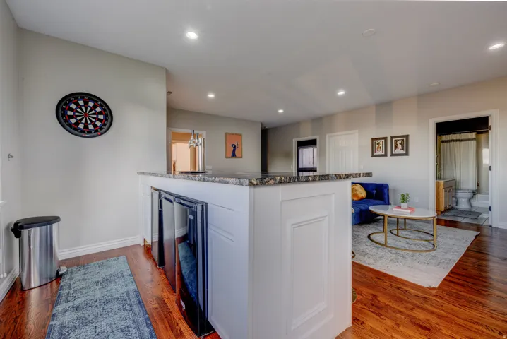 Built-in bar with granite countertop, integrated beverage refrigerators, and recessed lighting