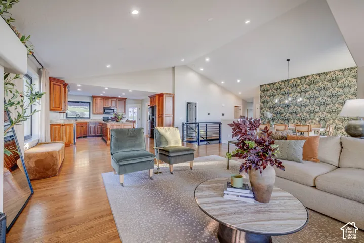 Open-concept living area with vaulted ceilings, recessed lighting, wood-finish flooring, and a kitchen featuring wood cabinetry and an island