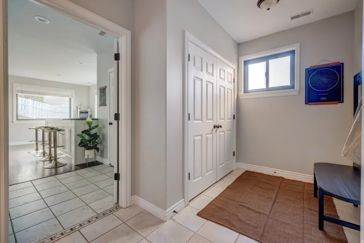 Tiled flooring with decorative border, white bi-fold closet doors, and a window with white trim