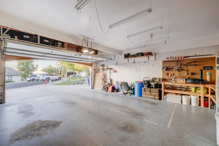 Spacious garage featuring a concrete floor, overhead storage, and fluorescent lighting
