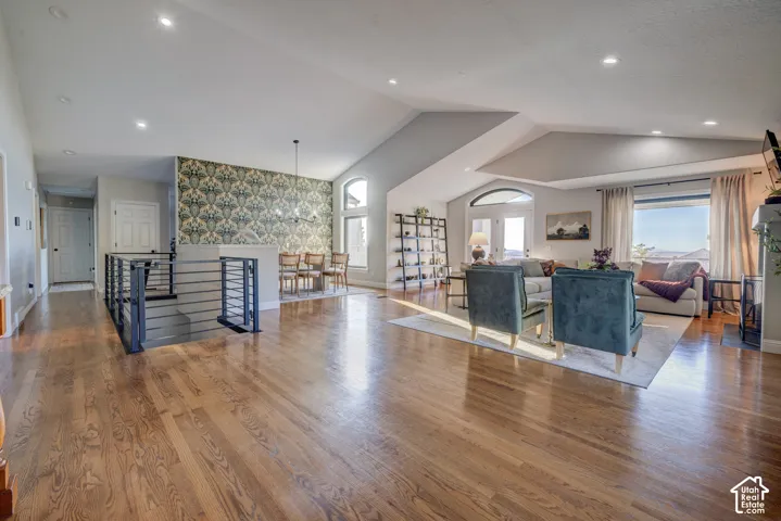 Wood-finish flooring throughout, modern stair railing, vaulted ceiling, recessed lighting, and expansive windows
