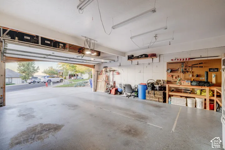 Spacious garage featuring a concrete floor, overhead storage, and fluorescent lighting