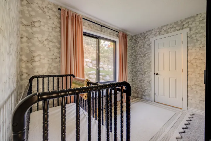 White interior door with panel detailing, patterned wall covering, and a window with natural light