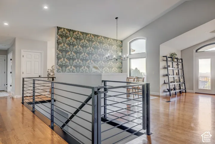 Hardwood flooring, wrought iron railing, vaulted ceilings, arched windows, and a decorative accent wall
