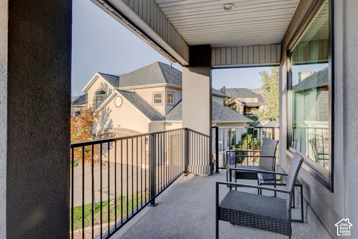 Balcony featuring a black metal railing, concrete flooring, and a textured stucco exterior wall