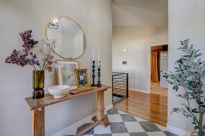 Black and white checkered tile flooring, wood-finish flooring, and a contemporary black metal stair railing