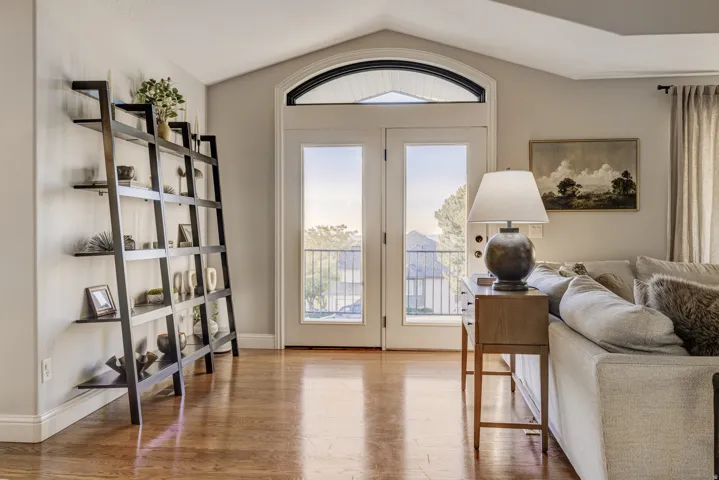 Vaulted ceiling with an arched transom window, French doors, wood-finish flooring, and crown molding