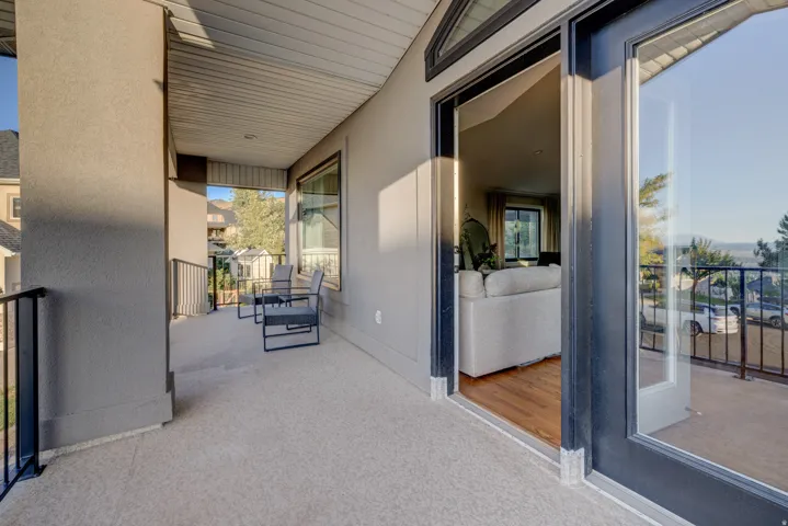 Covered balcony with a textured concrete surface, black metal railings, and a wood-finish ceiling