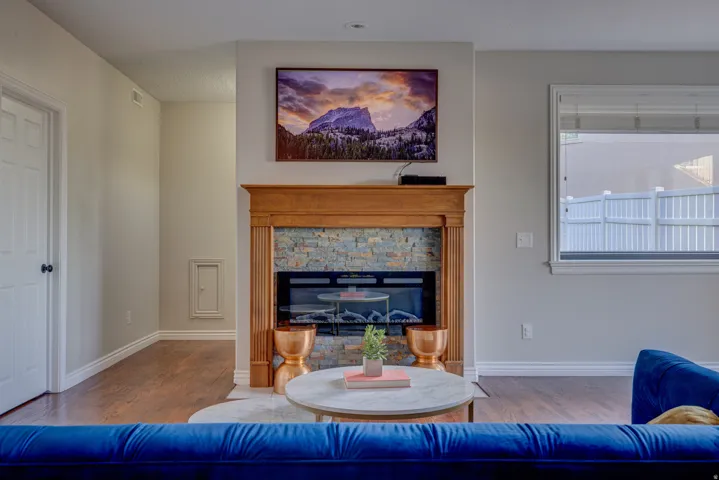 Hardwood-style flooring extends throughout, complementing the fireplace featuring a wood mantel and stone surround
