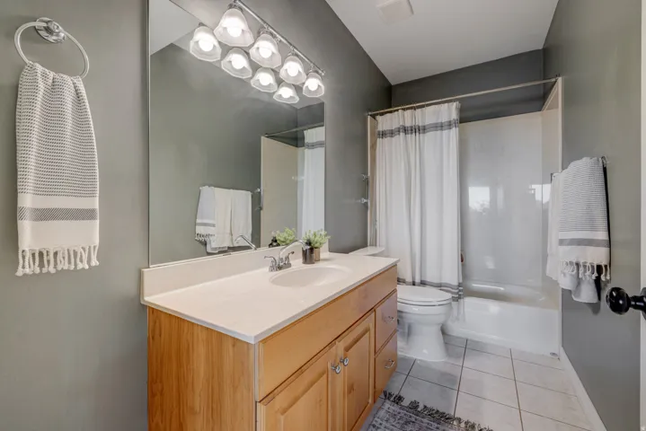 Single vanity with light wood-finish cabinetry, white countertop, and integrated sink
