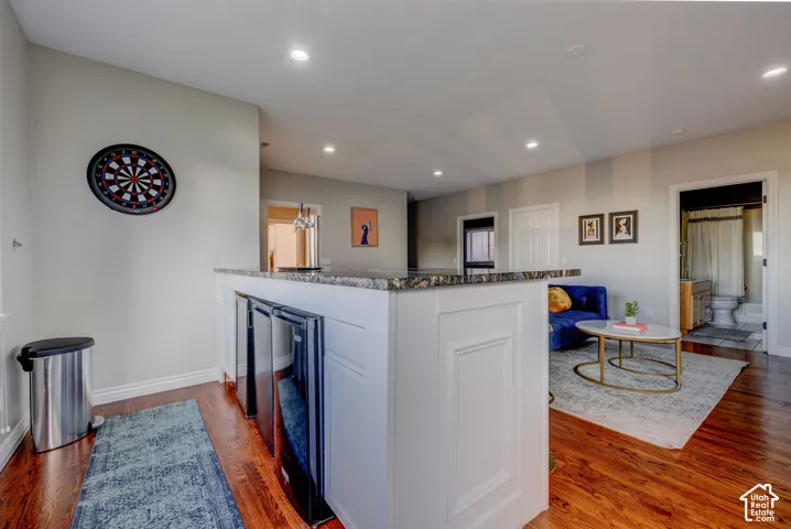 Built-in bar with granite countertop, integrated beverage refrigerators, and recessed lighting