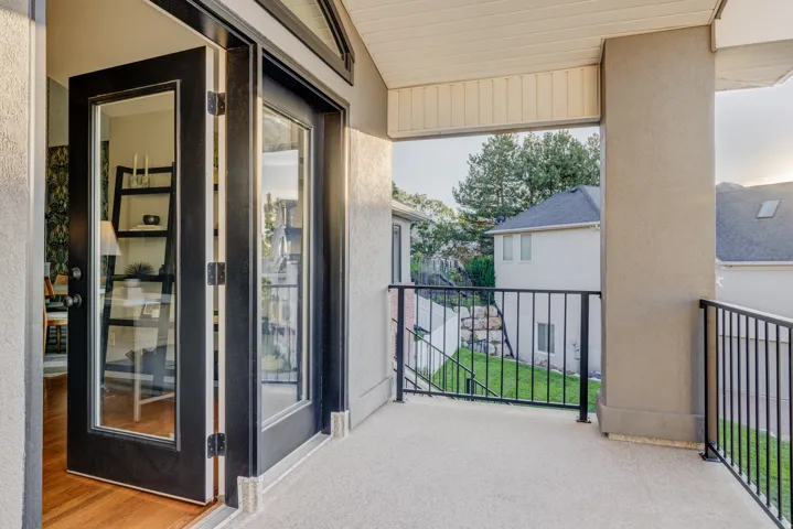 Private balcony with black iron railings, textured concrete flooring, and an overhead soffit