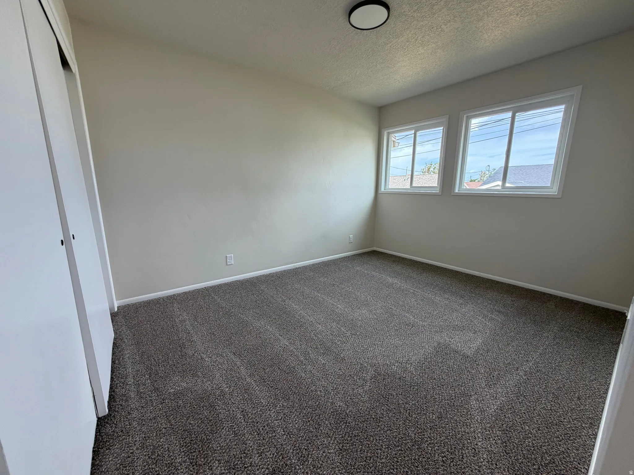 Neutral wall color, dual pane windows, textured carpeting, overhead flush-mount lighting, and white trim