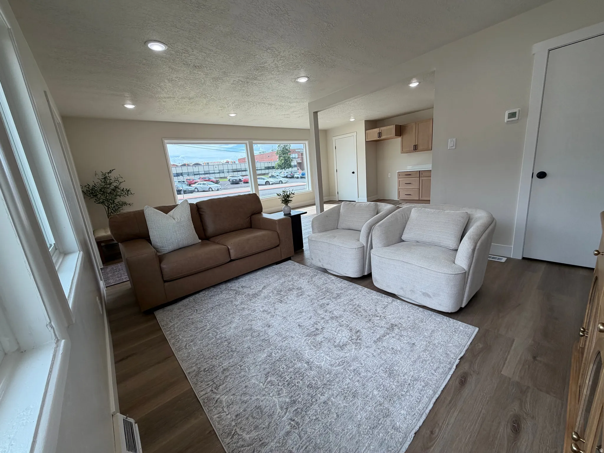 Recessed lighting, wood-finish flooring, light-toned wall paint, white trim, and a partial view of kitchen cabinetry