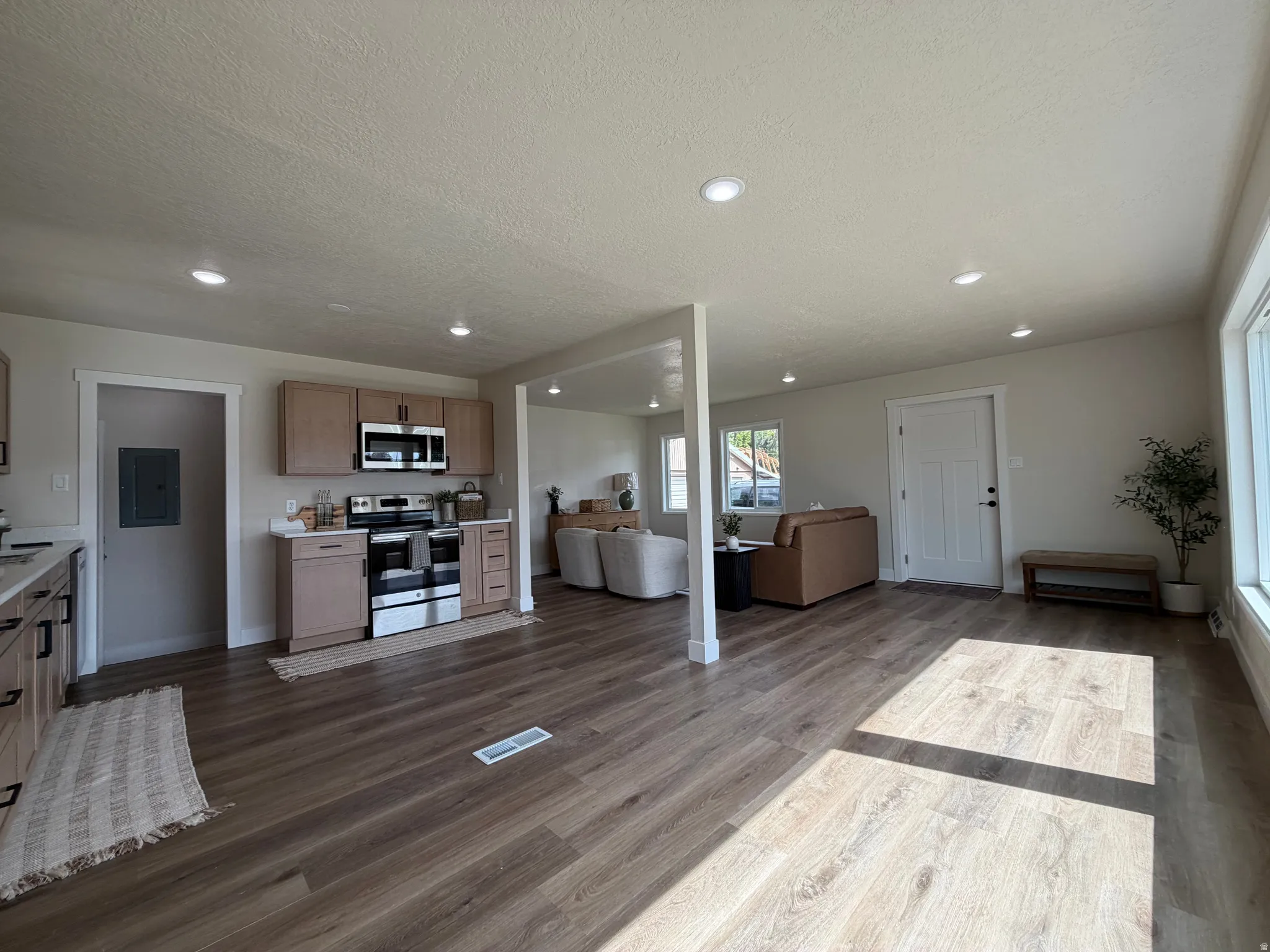 Open-concept living space with wood-finish flooring, recessed lighting, and ample natural illumination