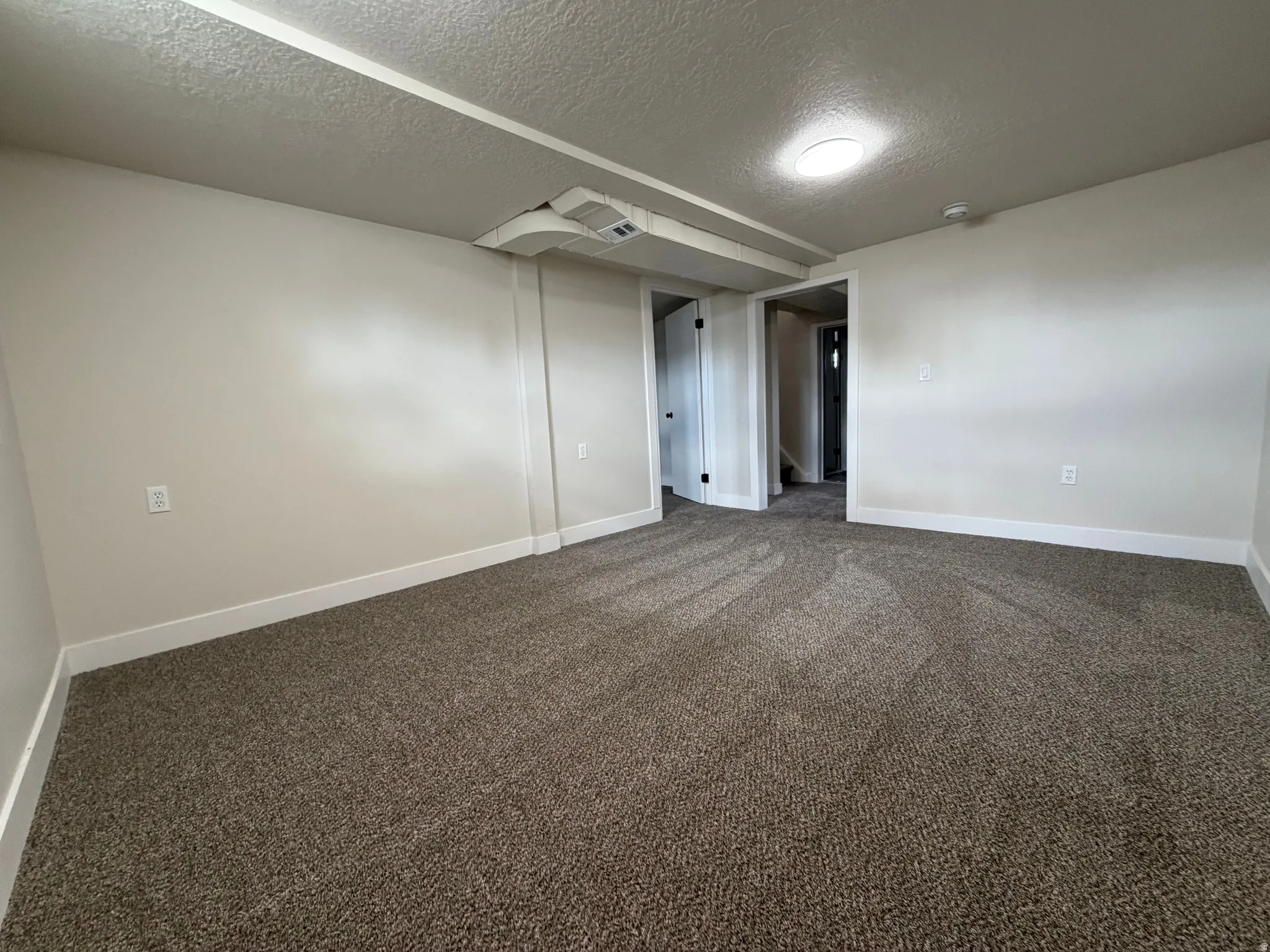 Neutral-toned walls complement the textured carpet flooring