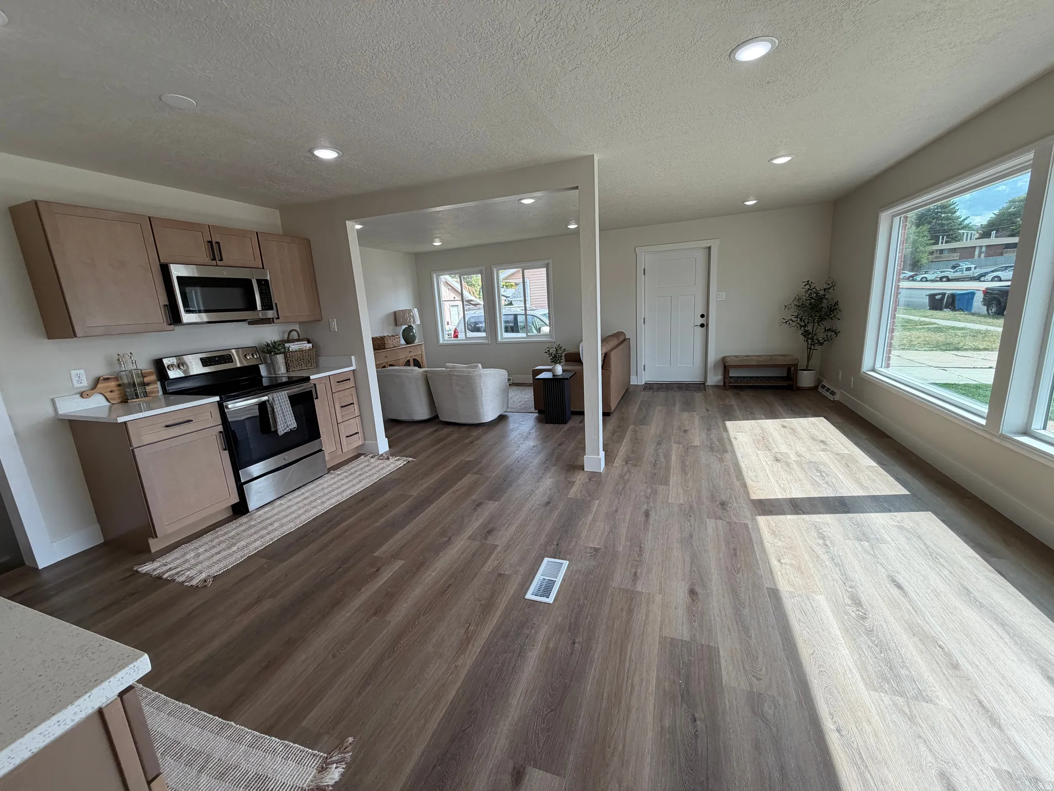 Spacious open-concept interior featuring wood-finish flooring, recessed lighting, and large windows