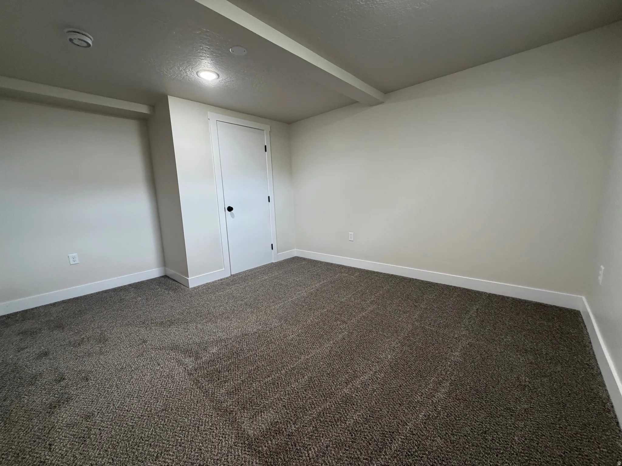 Neutral wall tones with recessed lighting, complemented by patterned carpeting and white trim
