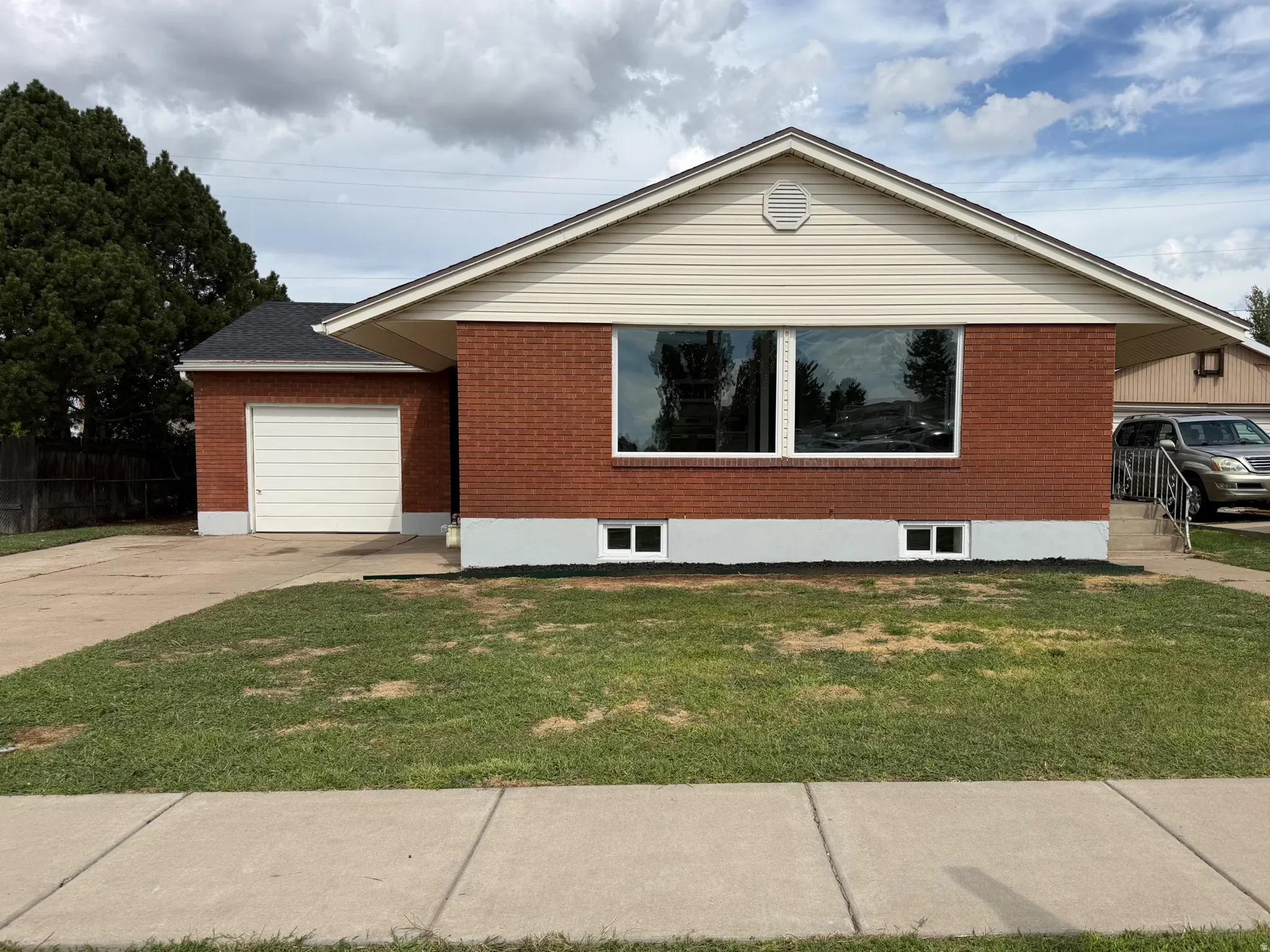 Brick exterior with light-colored siding, attached single-bay garage, and concrete driveway