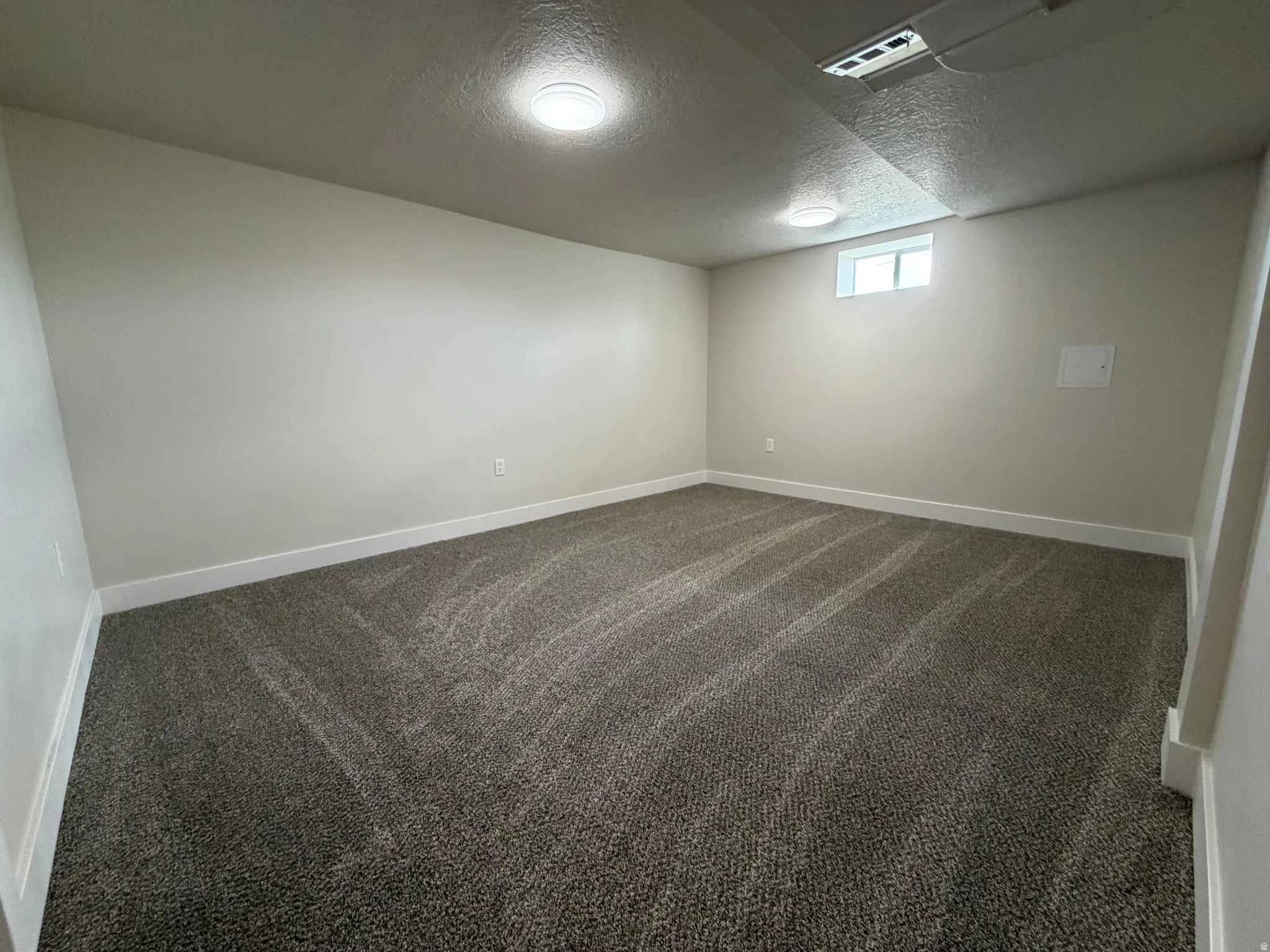Recessed ceiling lighting, light-colored walls, patterned carpet flooring, and a single window