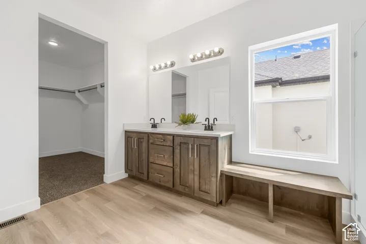 Dual sink vanity with wood-finish cabinetry, quartz countertop, and matte black fixtures