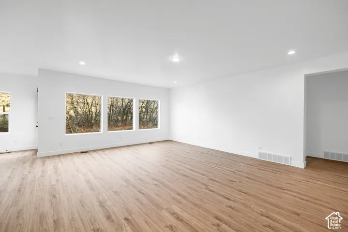 Wood-finish flooring, recessed ceiling lighting, multiple large windows, white walls, and white trim