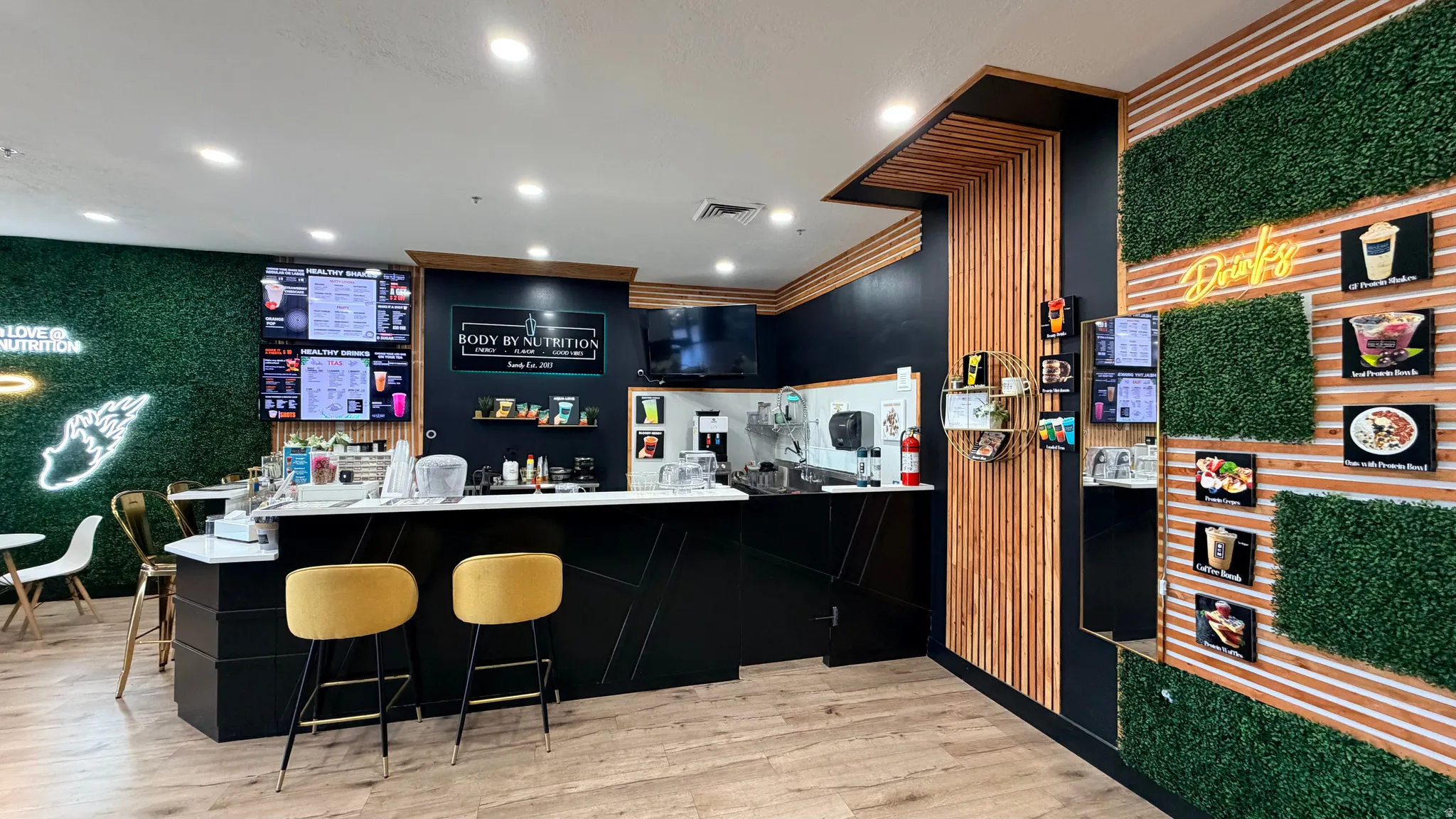 Modern service counter with a stone-finish countertop, wood-finish flooring, and accent walls featuring wood slat and faux greenery panels