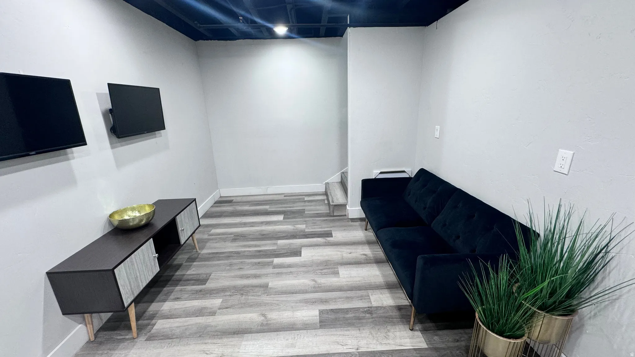 Wood-finish flooring with light gray walls, an exposed dark ceiling, and recessed lighting